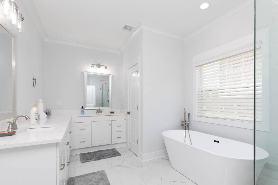Complete bathroom remodel featuring white vanities, tile flooring and a large soaking tub
