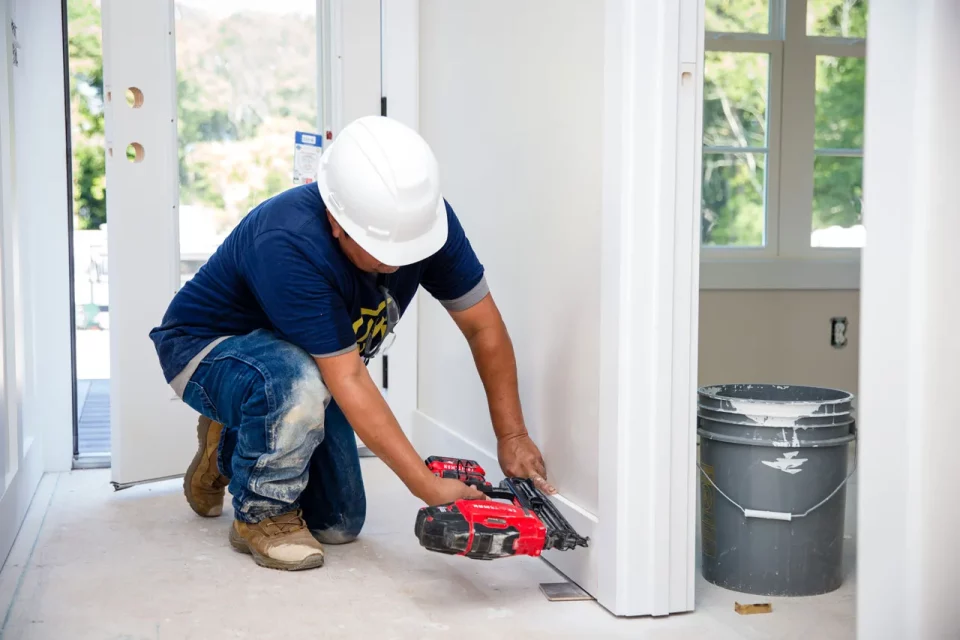 A service professional installs a white baseboard during a home remodel by Wade Construction in Rock Hill, SC