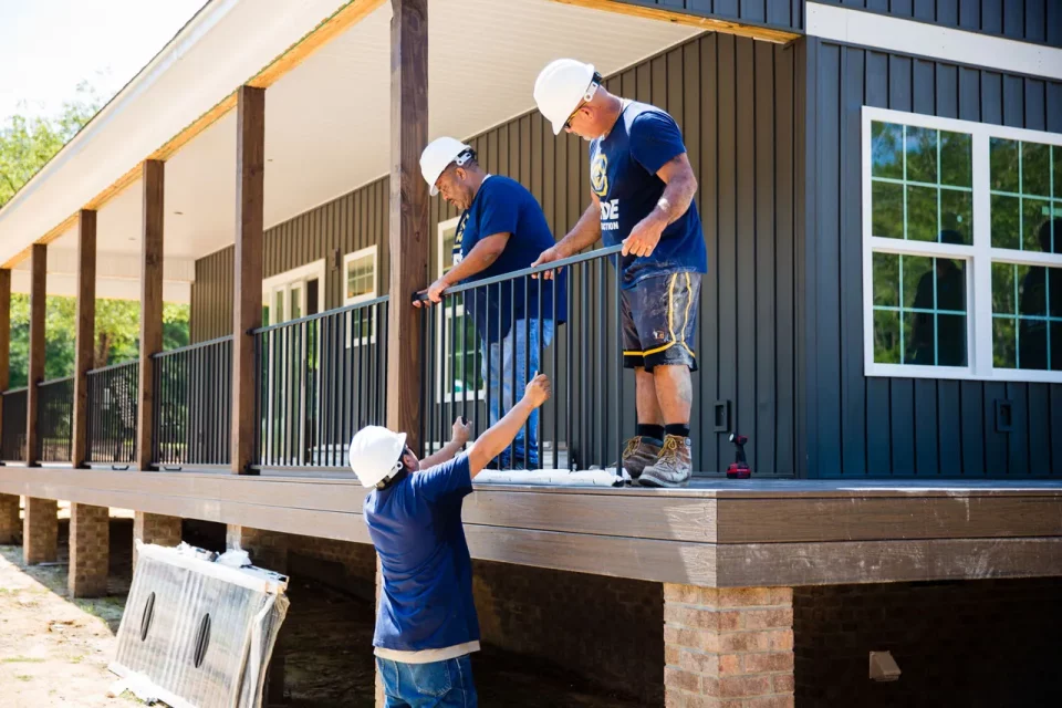 Wade Construction team members install a metal railing on a wrap around porch