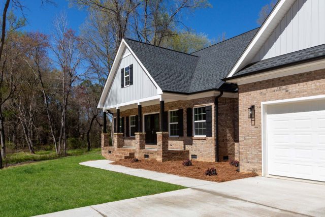 Angled view of newly built home featuring white siding and light brick exterior by Wade Construction in Rock Hill, SC