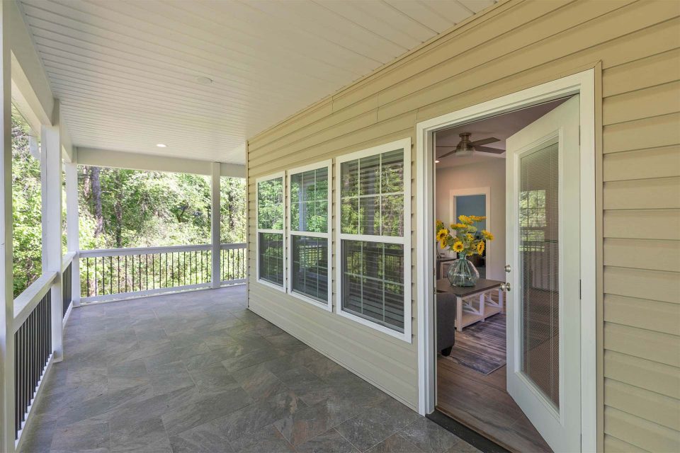 Beautiful covered wrap around porch featuring white beams and metal railing by Wade Construction in Rock Hill, SC