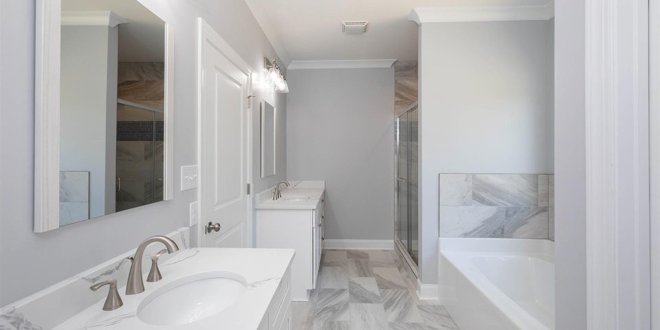 Complete bathroom remodel featuring double white vanities, soaking tub and tile flooring by Wade Construction in Rock Hill, SC