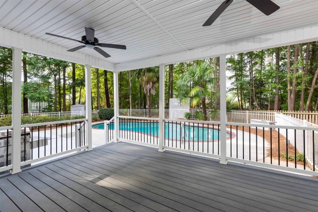 Large covered porch with ceiling fans overlooking a beautiful pool and bbq