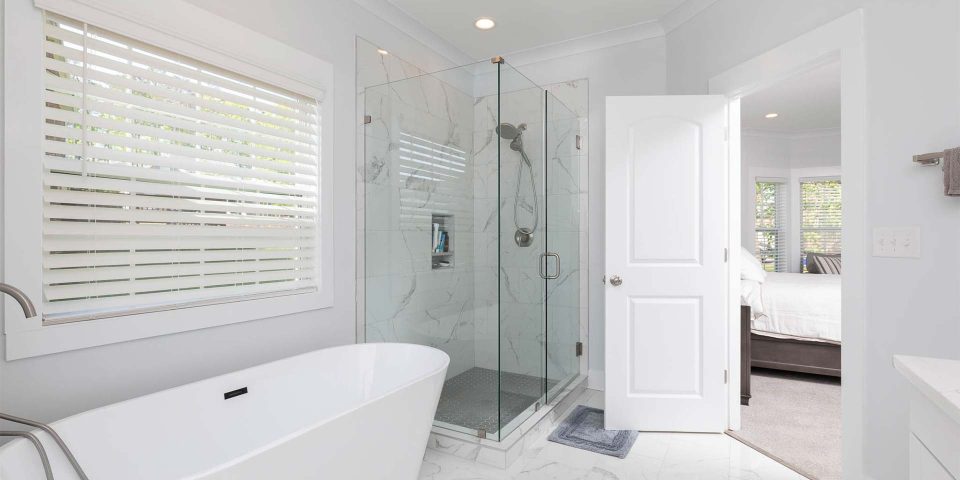 Complete bathroom remodel featuring soaking tub, glass framed shower and white vanities designed and installed by Wade Construction of Rock Hill, SC
