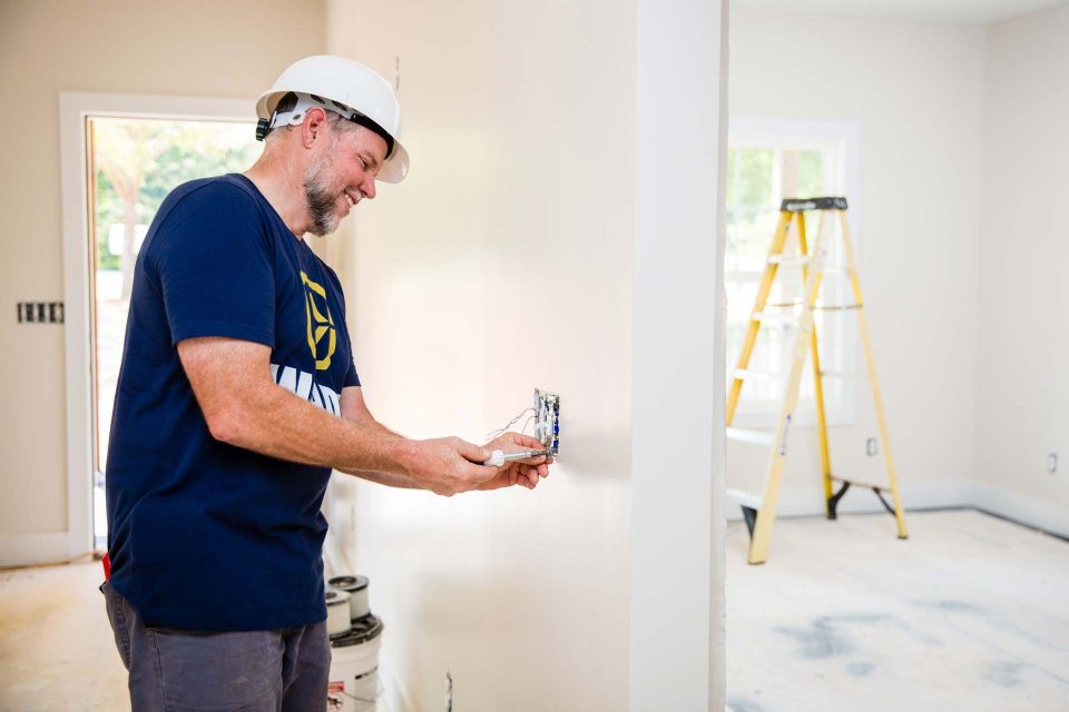 An experienced residential electrician wires an electrical socket in a new construction home