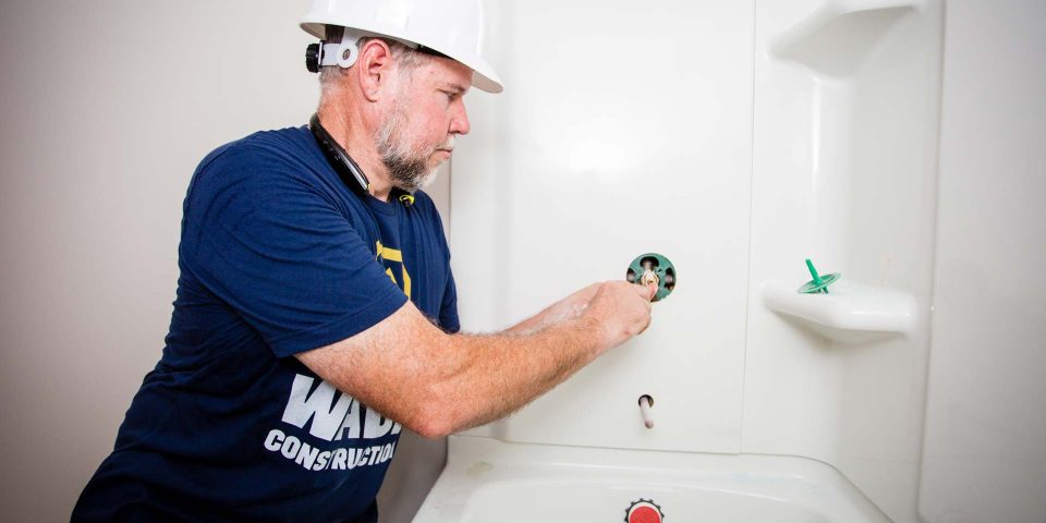 A plumber prepares to install a shower faucet handle in a new tub