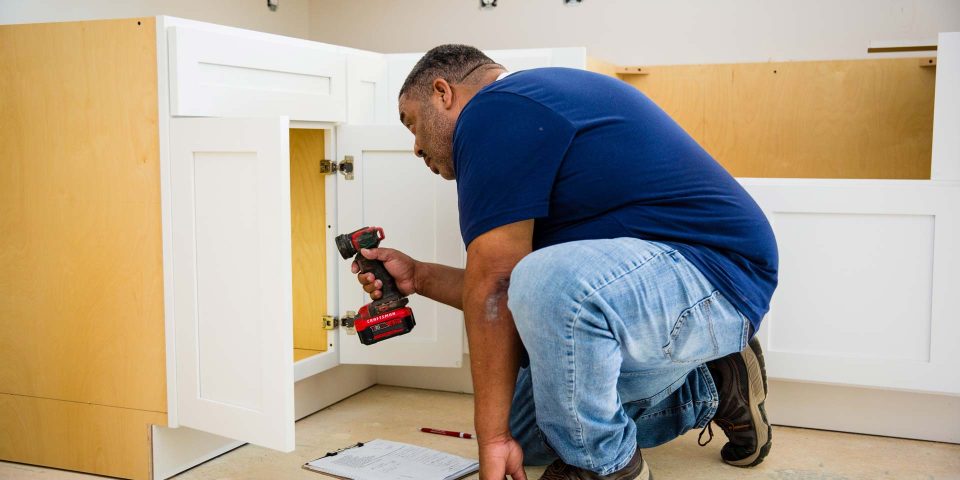 A man reviews a newly installed kitchen cabinet while performing a home inspection