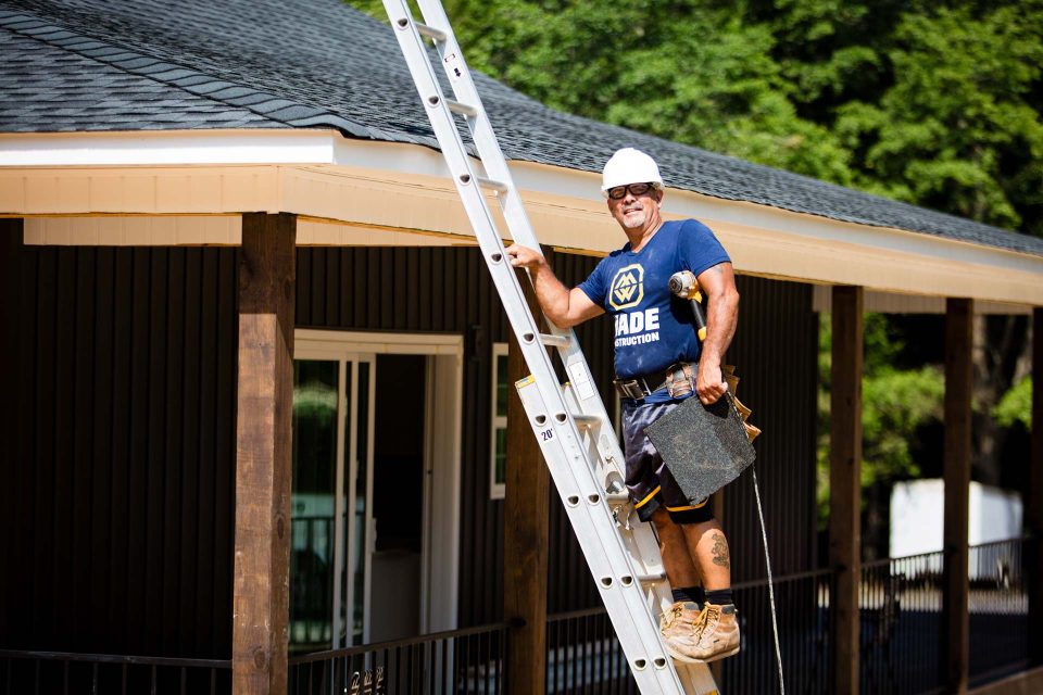 A roofing contractor for Wade Construction of Rock Hill, SC stands on a ladder as he prepares to make repairs to a residential roof