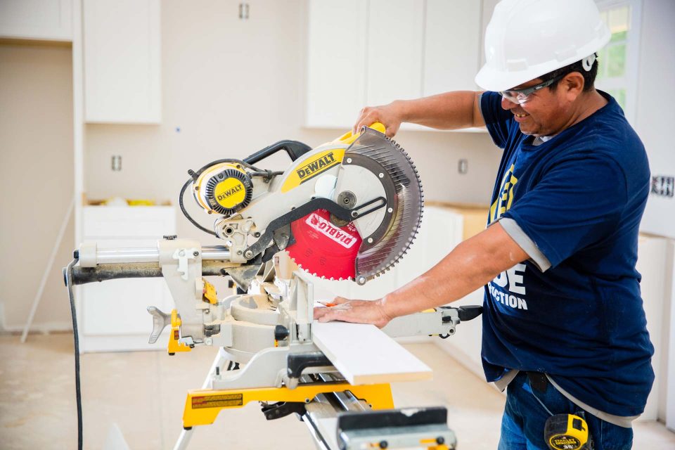 A Wade Construction employee prepares to cut a piece of lumber with a circular saw