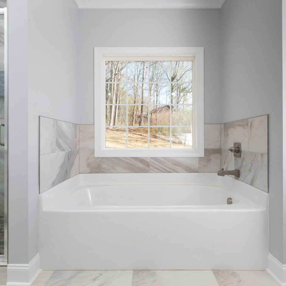 New construction bathroom with white bathtub and stone accents designed and installed by Wade Construction of Rock Hill, SC