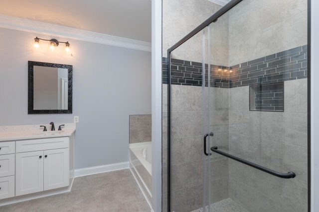Bathroom remodel featuring glass framed shower and white vanities designed and installed by Wade Construction of Rock Hill, SC