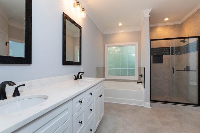 Bathroom remodel featuring glass framed shower, white vanity, and nicely contrasting black fixtures designed and installed by Wade Construction of Rock Hill, SC