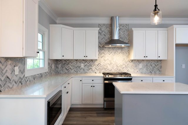 Kitchen remodel featuring large island with white countertop and gray backsplash