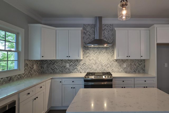 Kitchen remodel featuring large island with white countertop and gray backsplash