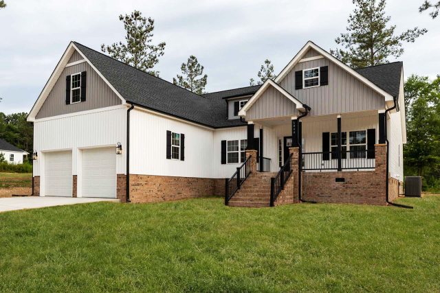 New construction home with vertical gray and white siding, and brick foundation built by Wade Construction in Rock Hill, SC
